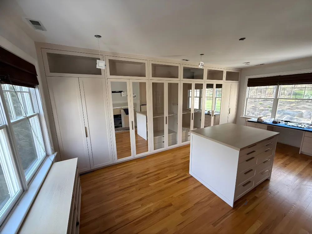 Custom walk-in closet installation featuring mirrored doors and storage wall