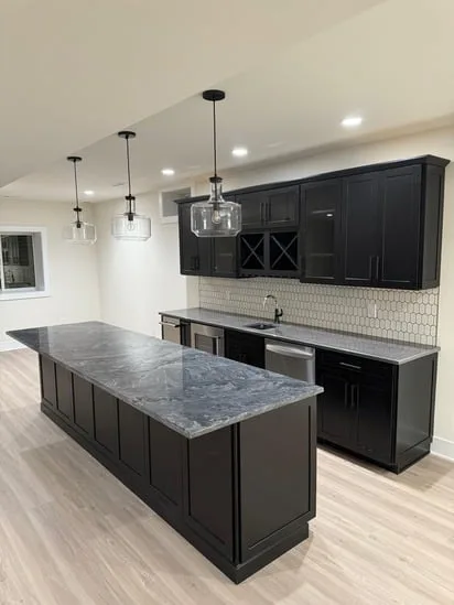 An angled perspective of the custom bar cabinets and island, showing the overhead pendant lighting and the overall layout of the space.