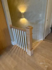 View of the completed finished stair carpentry project, showcasing the installation from a side angle, integrating a custom newel post, balusters, and matching railing elements.