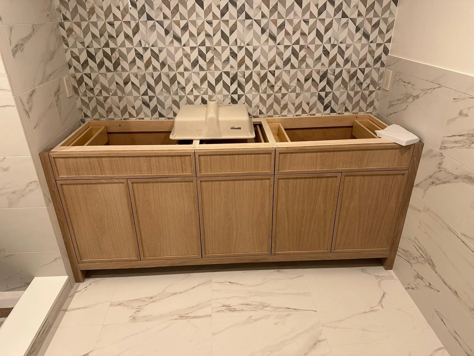 Professional custom vanity carpentry installation showing a handcrafted wood cabinet fitted against a geometric tile wall.